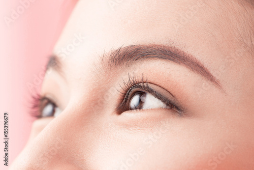 Beautiful asian woman eye with long eyelashes isolated on pink background. photo