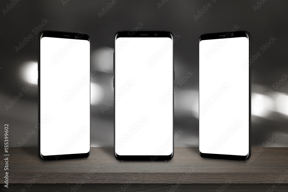 Three mobile phones with isolated screen for mockup on the table. Bokeh lights in background.