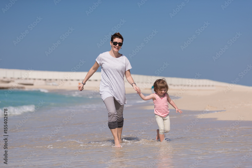 mother and daughter running on the beach