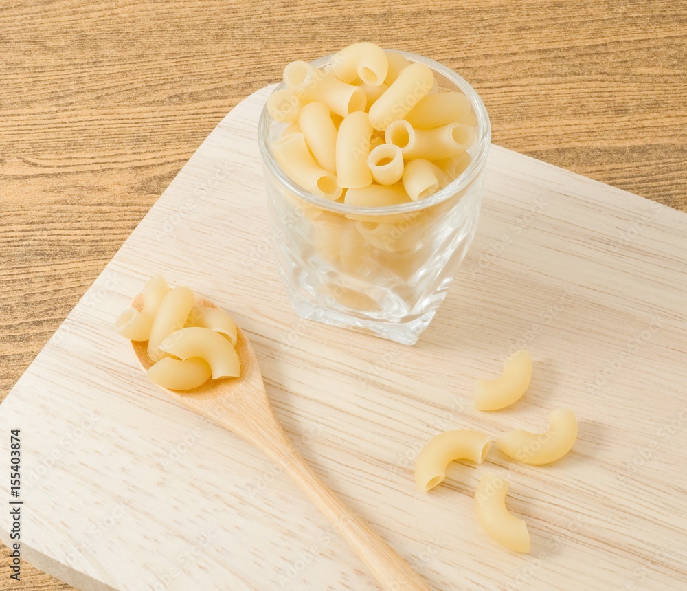 Elbow Macaroni or Gomiti Pasta on A Wooden Cutting Board