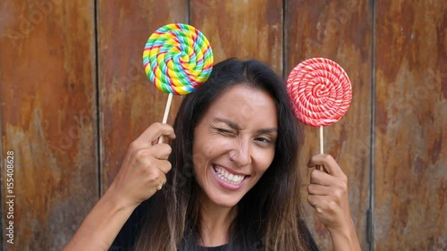 Cheerful Young Woman with Colorful Lollipops Making Minnie Mouse Ears From Candies. Slow Motion. HD, 1920x1080. photo