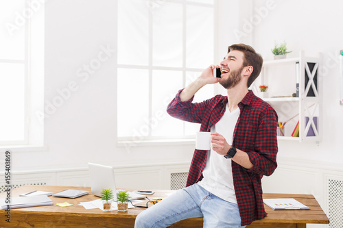 Happy and relaxed businessman talk mobile in office