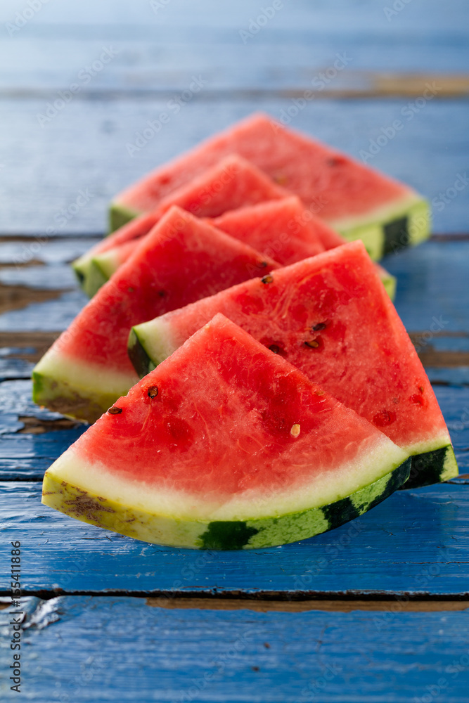 Sliced watermelon closeup. Many slices on an old rustic blue table. Side composition with copy space. Sliced watermelon closeup. Many slices on an old rustic blue table. Side composition with copy space.