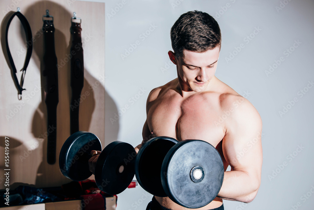 Close-up of handsome power athletic man training pumping up muscles with dumbbells Close-up of handsome power athletic man training pumping up muscles with dumbbells