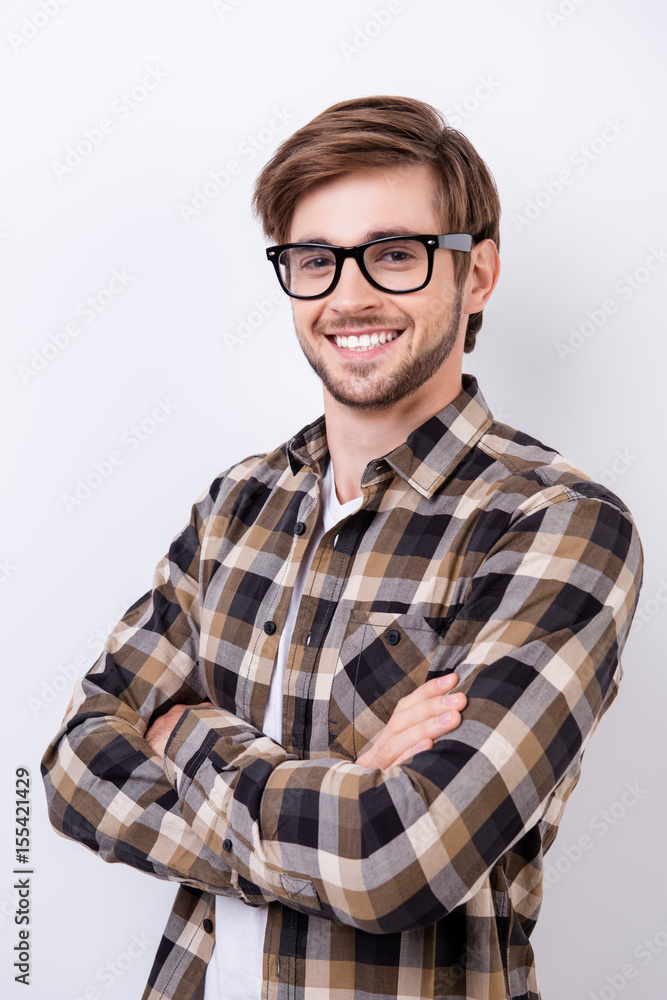 Successful young bearded handsome student is smiling. He is in a casual outfit on pure background with crossed hands Successful young bearded handsome student is smiling. He is in a casual outfit on pure background with crossed hands
