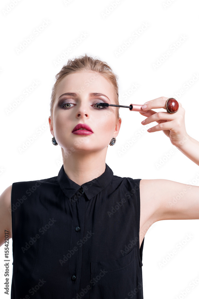 Obraz premium Beautiful young woman applying mascara with brush, studio beauty portrait. Applying cosmetic, eyes makeup. Dark evening make-up and jewelry in beauty concept. Fashion photo