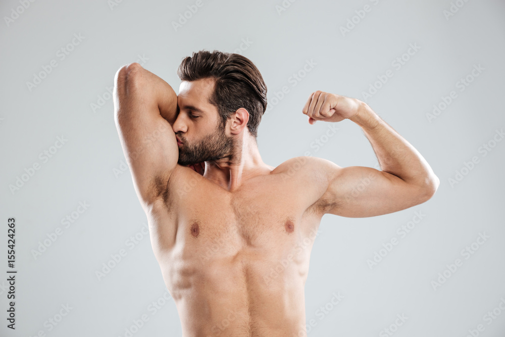 Handsome young naked man showing and kissing his biceps Handsome young naked man showing and kissing his biceps