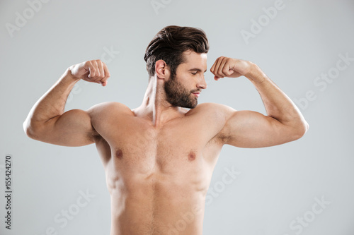 Tableau sur toile Confident man showing his biceps and looking at camera