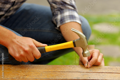Obraz na plátne Casual man hammering nail in plank at home