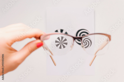 Woman's hand holding eyeglasses and checking for astigmatism