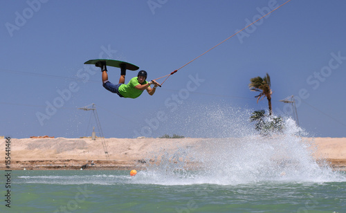 Wake boarding sportsman jumping high in the cable park, water sports, active life style