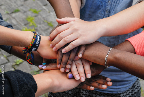 Multiracial teenagers joining hands together in cooperation photo