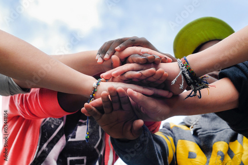 Multiracial teenagers joining hands together in cooperation