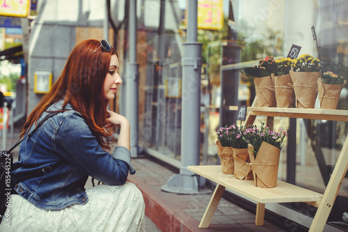 Young woman buys flowers on the street, modern packaging in trend, soft evening light