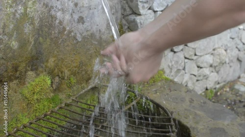 Hand scooping fresh water in pure mountain spring photo