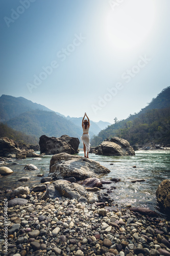 Woman making yoga on a bank of river