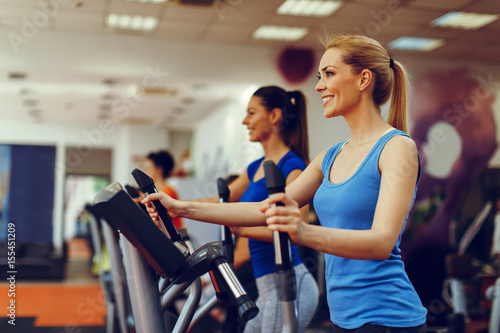 Two young woman exercising on stepper machine at gym