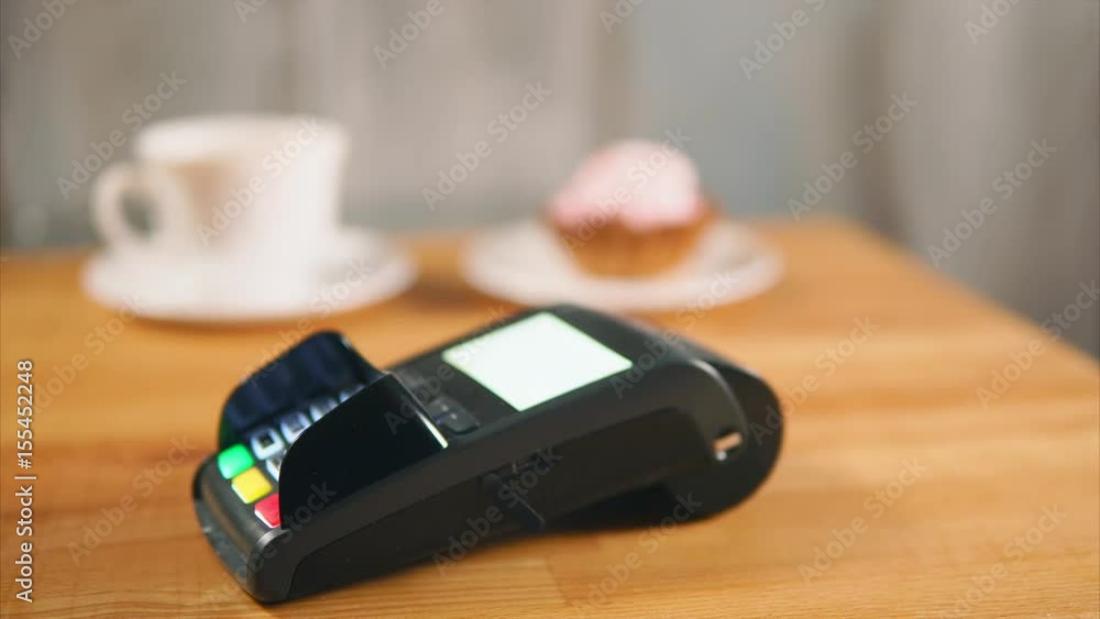 Close-up shot a customer paying in cafe with contactless credit card. Payments using NFC technology Close-up shot a customer paying in cafe with contactless credit card. Payments using NFC technology
