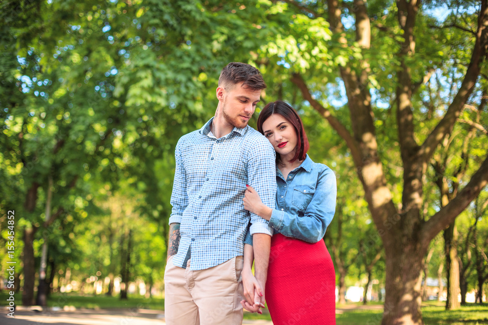 Happy young couple at park standing and laughing on the bright sunny day Happy young couple at park standing and laughing on the bright sunny day