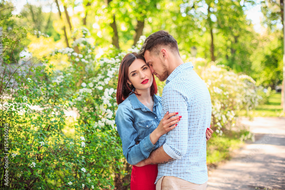 Fototapeta premium Happy young couple at park standing and laughing on the bright sunny day