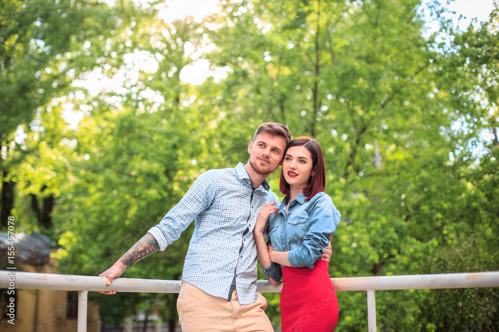 Naklejka premium Happy young couple at park standing and laughing on the bright sunny day