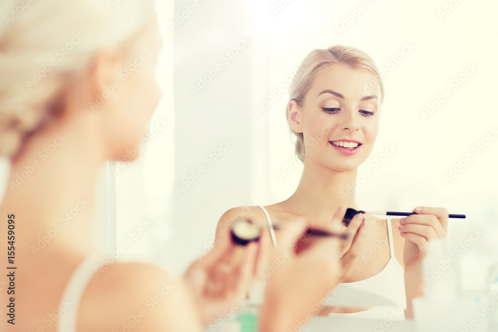 woman with makeup brush and eyeshade at bathroom woman with makeup brush and eyeshade at bathroom