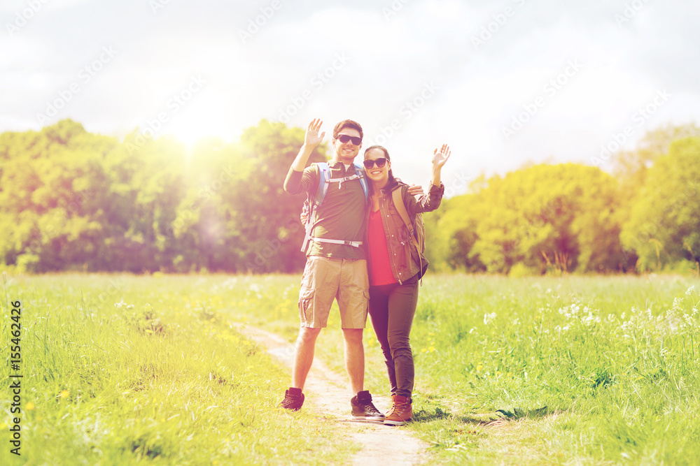 happy couple with backpacks hiking outdoors