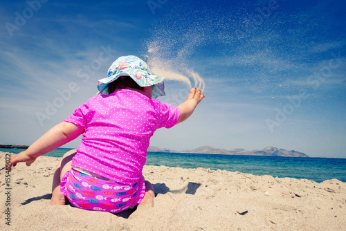 Little baby girl throw up sand with her hand.