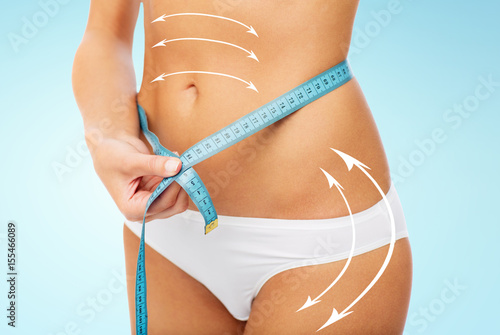 close up of woman body with measure tape on waist photo