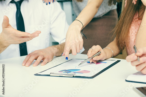 Group of business people looking at the clipboard with graphics.