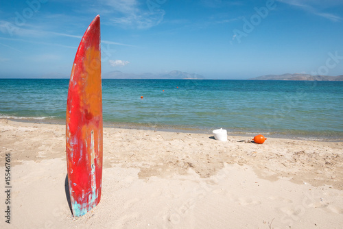 Surfboard stick on sandy beach as a sign of the water sports zone.