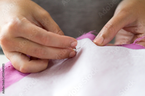woman with pins stitching paper pattern to fabric