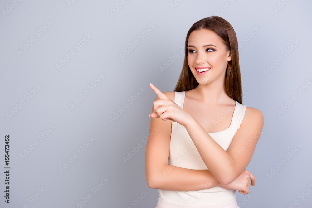 Cheerful cute model on blue background is pointing on a copy space, wearing casual clothes, smiling and looking away Cheerful cute model on blue background is pointing on a copy space, wearing casual clothes, smiling and looking away