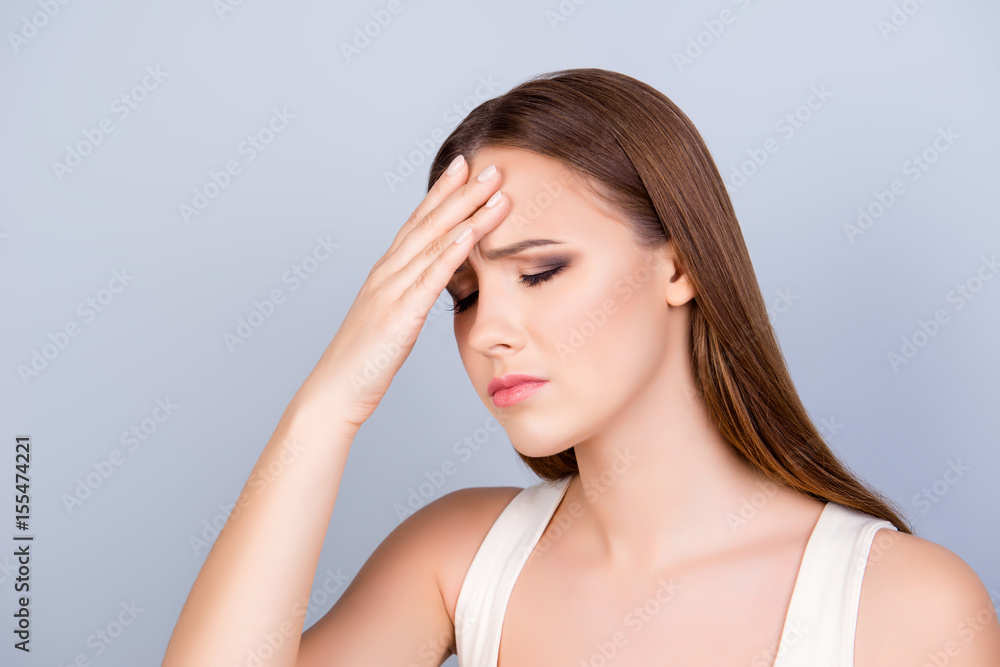Exhausted young cute lady is touching her forehead with closed eyes, she is tired and depressed,, isolated on pure light background