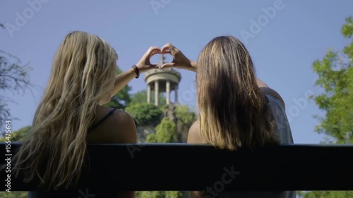 Young Women Create A Heart Shape With Their Hands, Around The Temple De La Sibylle In The Parc Des Butte Chaumont In Paris, France photo