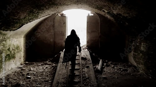Bearded man dressed in assassin's costume is exiting the ruined fortress.