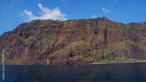 Madeira - Giant red cliffs and blue sky and ocean water from boat beneath Cabo Girao