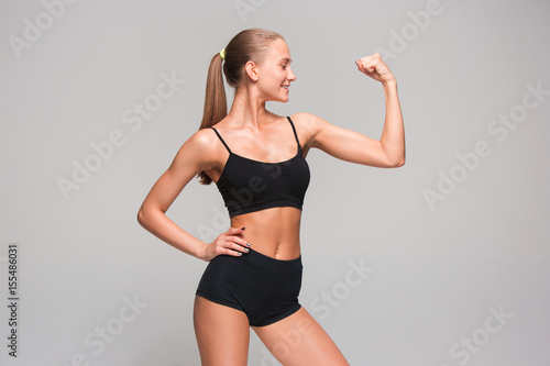 Muscular young woman athlete on gray