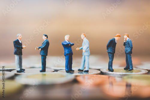 Miniature people businessman standing on money