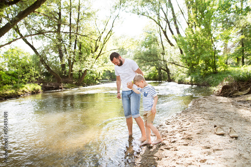 Young father with little boy at the river  sunny spring day.