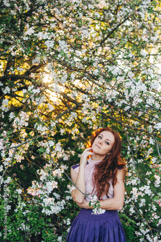 Red-haired girl with freckles near the apple tree Red-haired girl with freckles near the apple tree