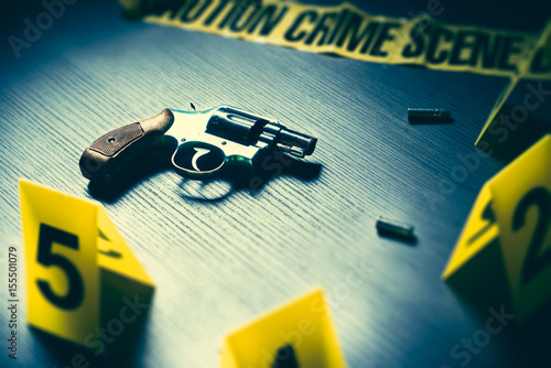 Photography dramatic lit crime scene with gun and markers on the floor