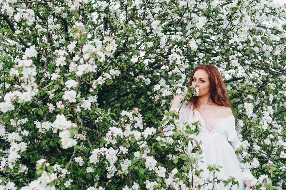Red-haired girl with freckles near the apple tree Red-haired girl with freckles near the apple tree
