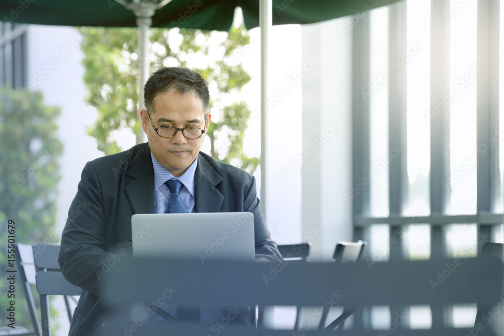 Executive businessman working with laptop computer at outdoor cafe Executive businessman working with laptop computer at outdoor cafe