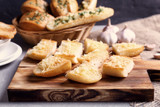 Tasty bread slices with garlic and cheese on wooden cutting board