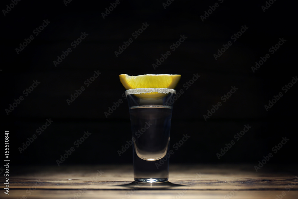 Tequila shot with juicy lemon slice and salt on dark background Tequila shot with juicy lemon slice and salt on dark background