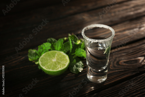 Tequila shot with juicy lime and salt on wooden background