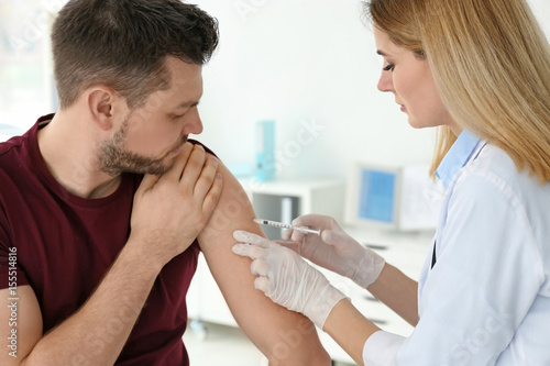 Slika na platnu Vaccination concept. Female doctor vaccinating young man