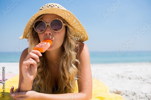 Woman eating popsicle while relaxing at beach photo