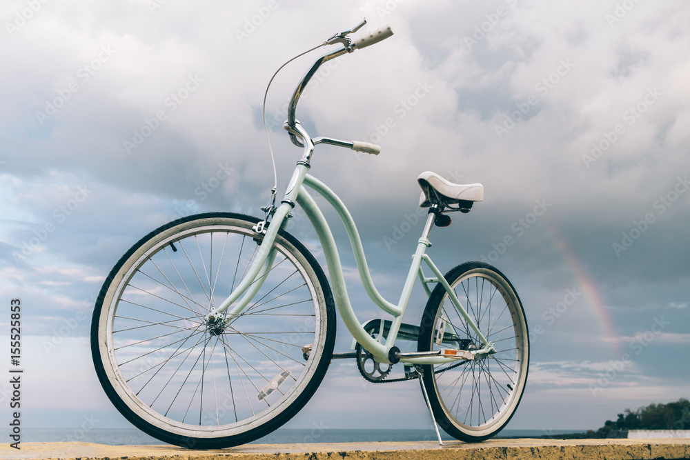 Fototapeta premium Vintage women's bike on the background of the sea and a rainbow